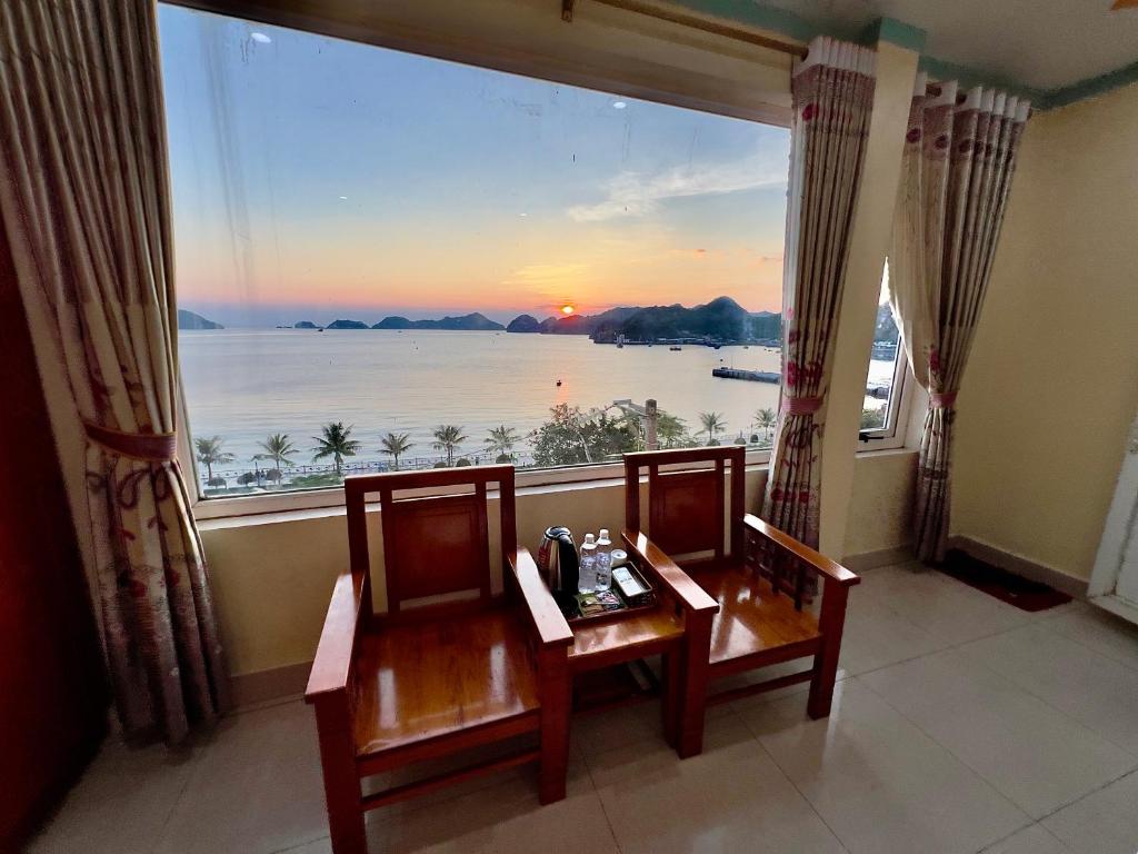 um quarto com 2 cadeiras e uma grande janela com vista em Manh Vuong Hotel em Ilha de Cát Bà