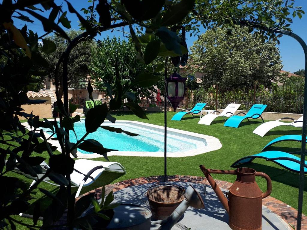 une cour arrière avec une piscine avec des chaises et une table et un arbre dans l'établissement Gîte Maison provençale Coeur du Var (rez-de-chaussée), à Gonfaron