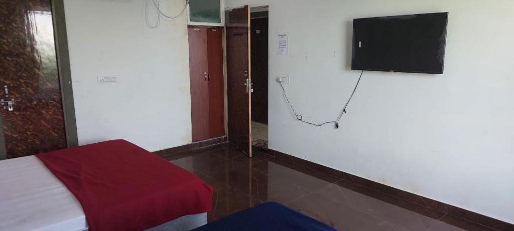 um quarto com uma cama e uma televisão na parede em Saritashray Seva Dham em Vrindavan