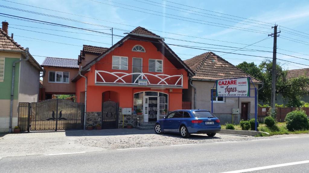 un coche azul estacionado frente a una casa roja en Casa Agnes Vendeghaz, en Fîntînele