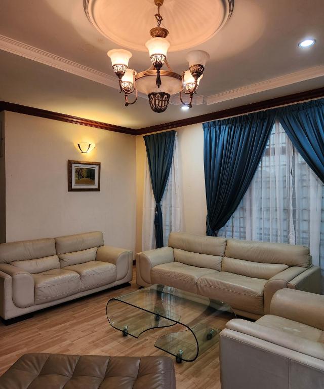 uma sala de estar com dois sofás e uma mesa de vidro em KB Homestay - Free WIFI em Kota Bharu