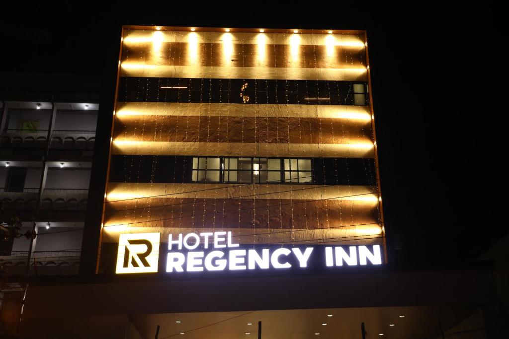 una señal de salida de emergencia del hotel frente a un edificio en Hotel Regency Inn, en Erode
