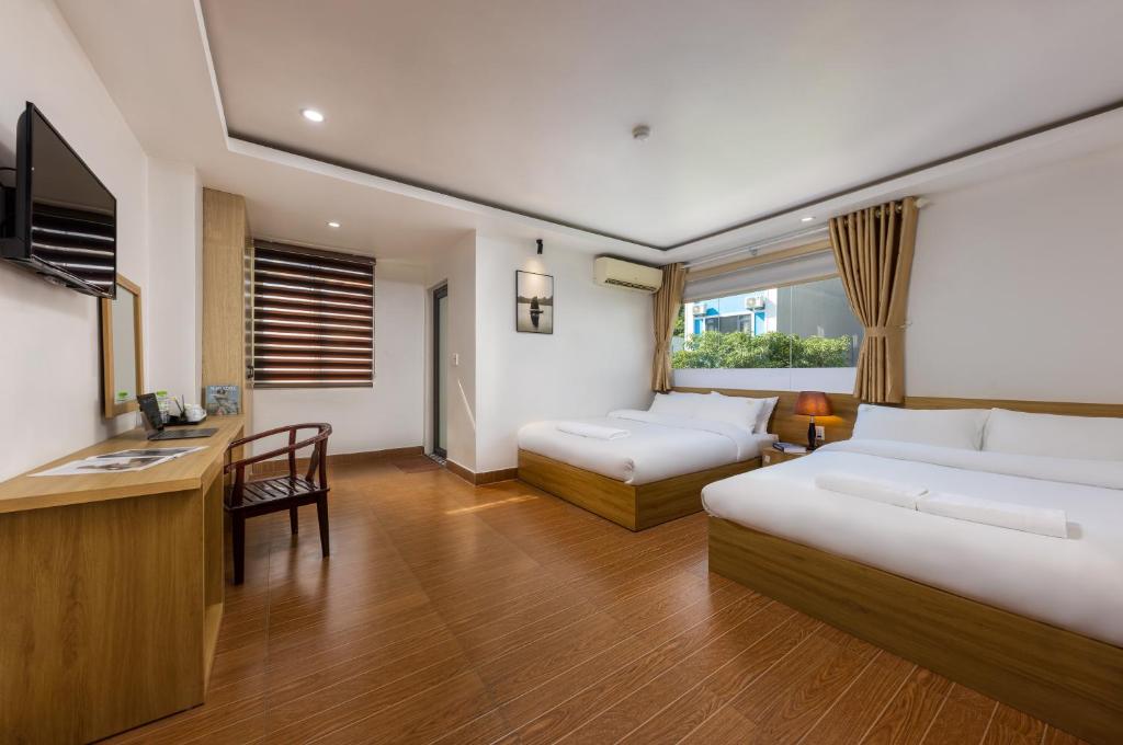 a hotel room with two beds and a desk at Cat Ba Hongkong Hotel in Cat Ba