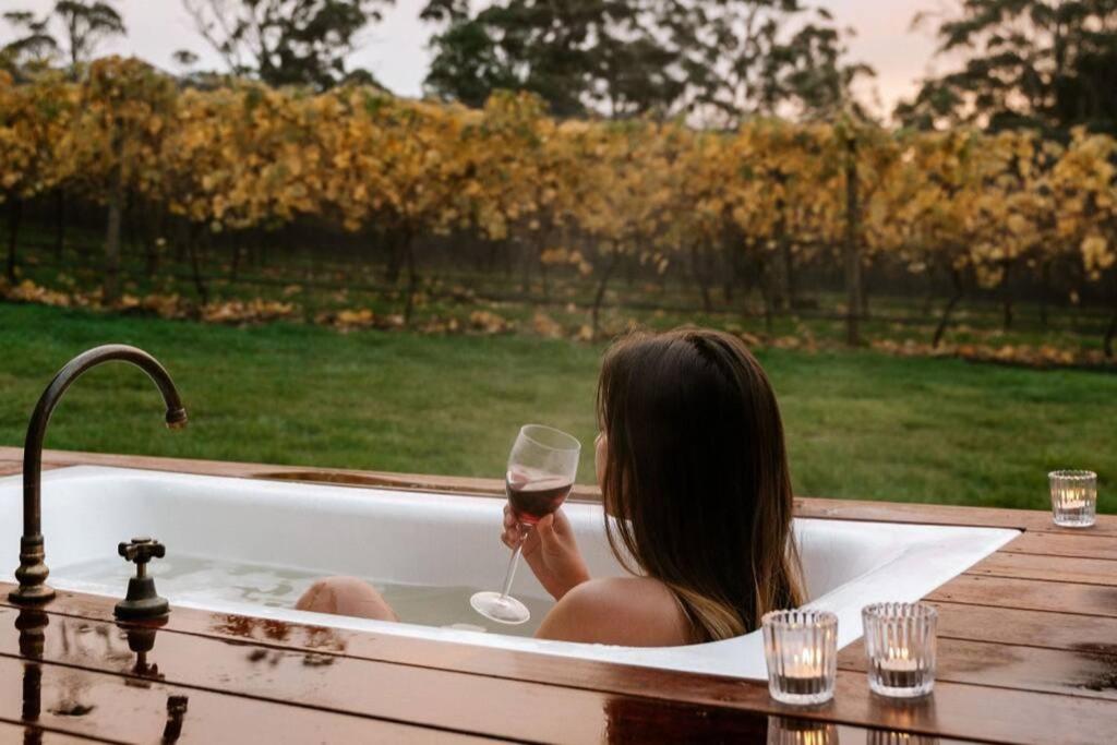 a woman sitting in a bath tub holding a glass of wine at Meander Valley Vineyard Escape in Red Hill