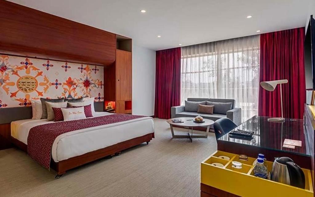 Triton By Shyama Hotels & Resorts في رايبور: غرفة فندقية بسرير كبير واريكة