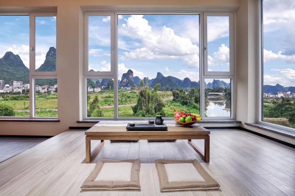 uma sala de estar com uma mesa e janelas grandes em Guilin Yangshuo Waterhouse River View Villa em Yangshuo