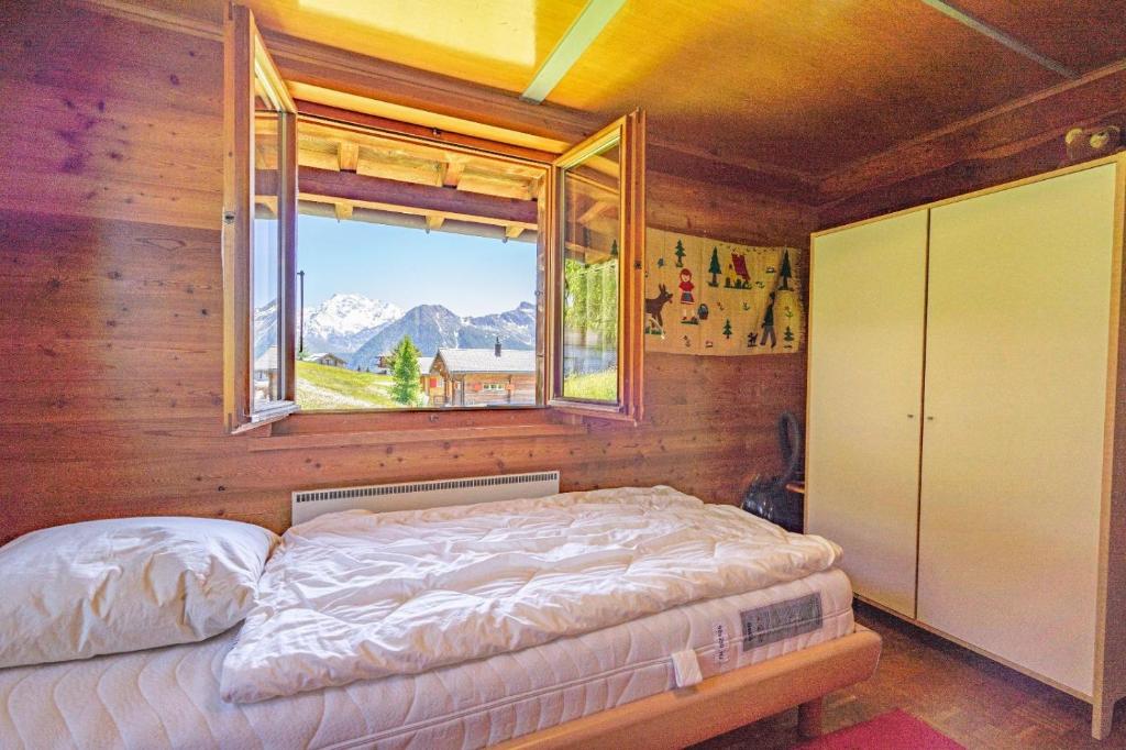 um quarto com uma cama com uma janela em Chalet Leiggener em Rosswald