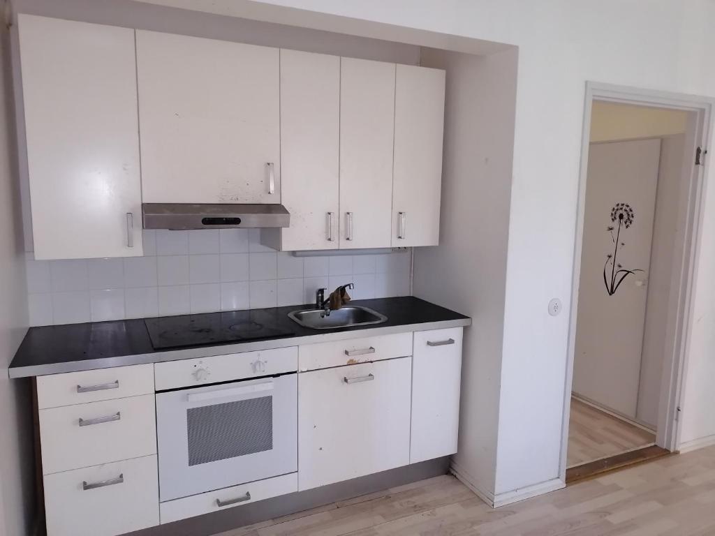 a kitchen with white cabinets and a sink at Apartments 15-20 block D in Kouvola