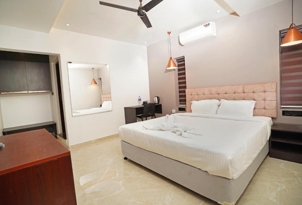 a bedroom with a large white bed and a desk at 7 The Business Hotel in Alwaye