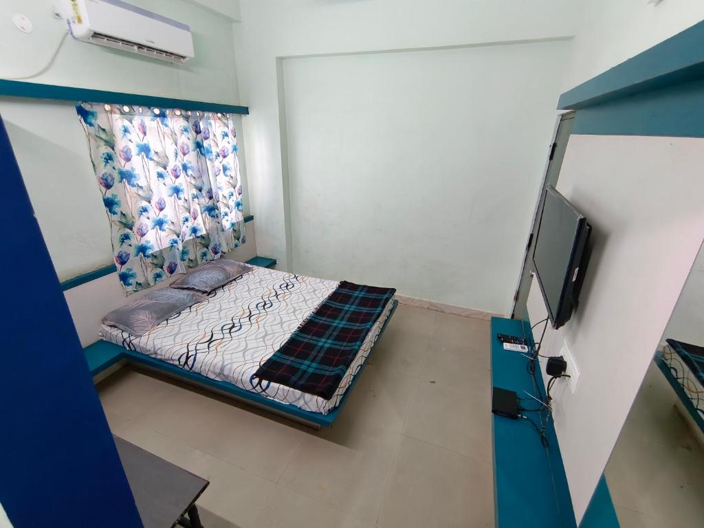 een kleine kamer met een bed en een televisie bij Sree Theja Residency in Anantapur