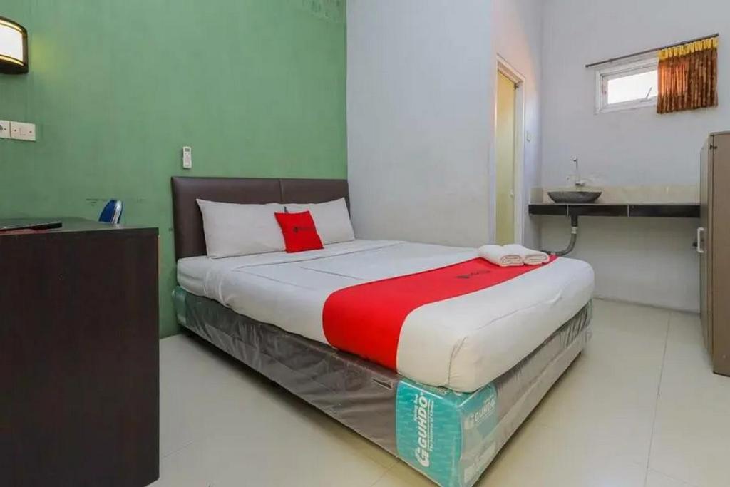 a bedroom with a bed with a red blanket on it at OYO 91292 Pondok Inap Shofwa 1 in Sidoarjo