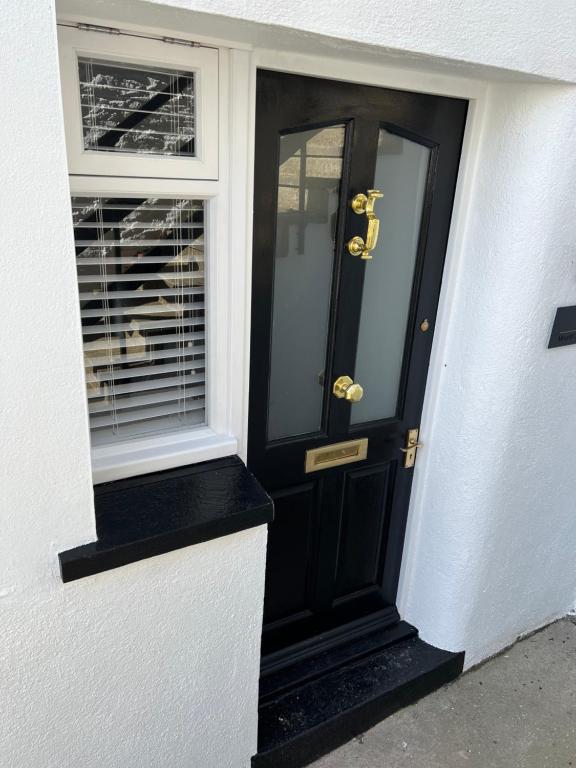 a black door with gold numbers on a white house at The Apartment Mount Galpine in Dartmouth