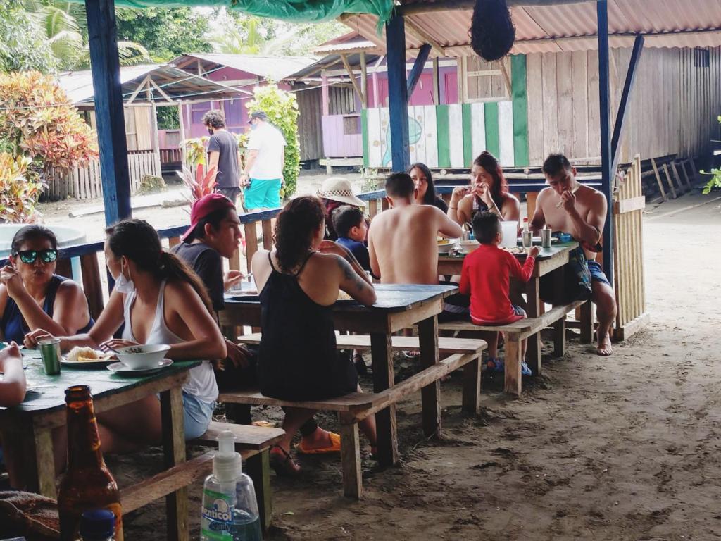 un grupo de personas sentadas en mesas en un restaurante en Cabañas en Playa la Barra, en Buenaventura