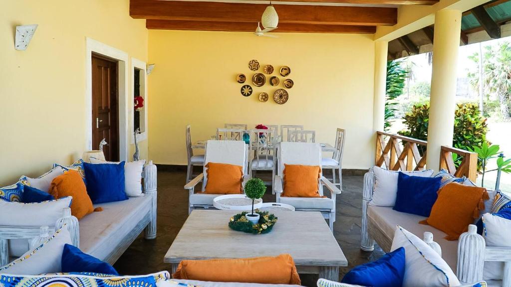 ein Wohnzimmer mit blauen und orangefarbenen Kissen und Stühlen in der Unterkunft Relaxing Beach Front Villa in Mambrui