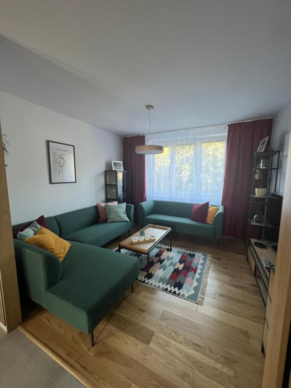 - un salon avec deux canapés verts et une table dans l'établissement Apartmán pod Lesom Kežmarok, à Kežmarok