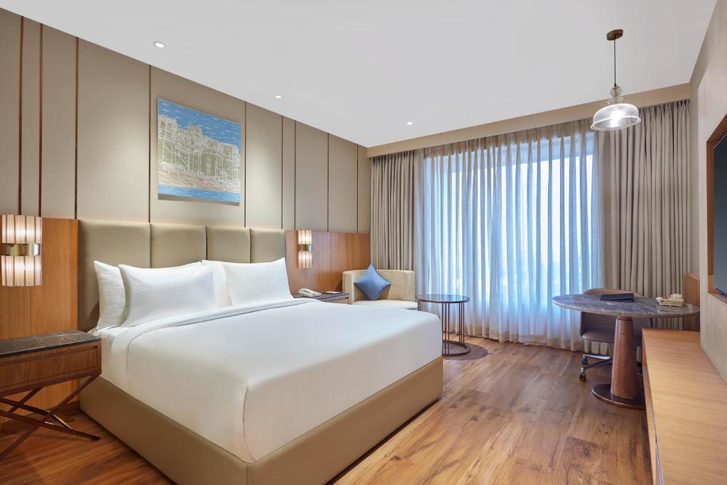 a bedroom with a large white bed and a desk at Doubletree By Hilton Varanasi in Varanasi