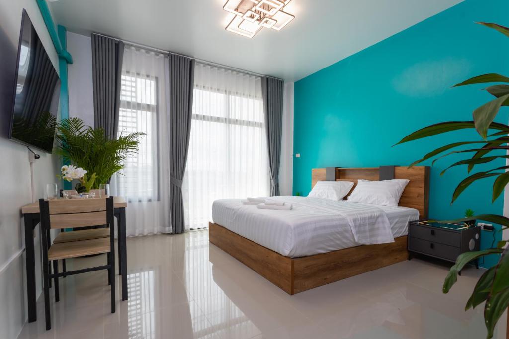 um quarto com uma cama e uma parede azul em Jen Sabaai em Ban Muang