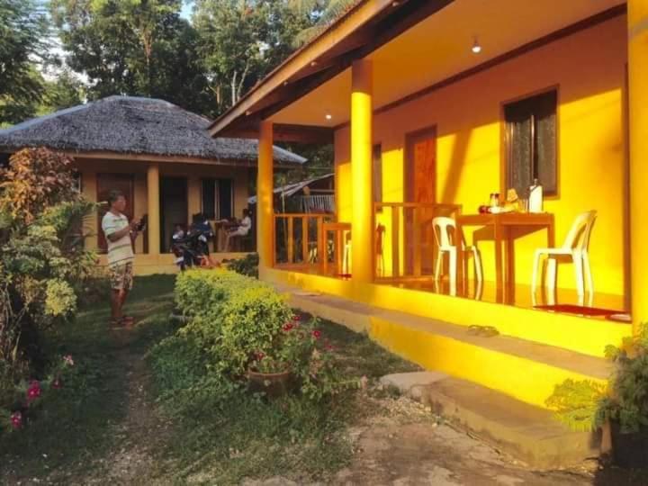 a person walking in front of a yellow house at Gold Star Inn in Siquijor