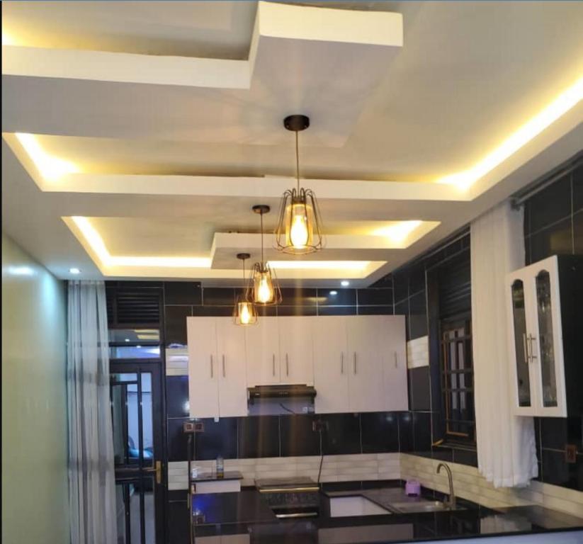 cocina con armarios blancos y techo con luces en IP House en Kigali