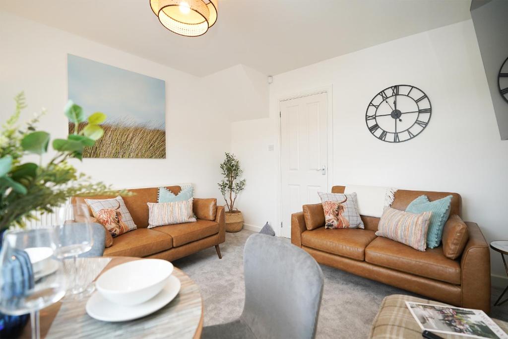 a living room with two brown couches and a table at Rural escape with peaks from your door in Sheffield