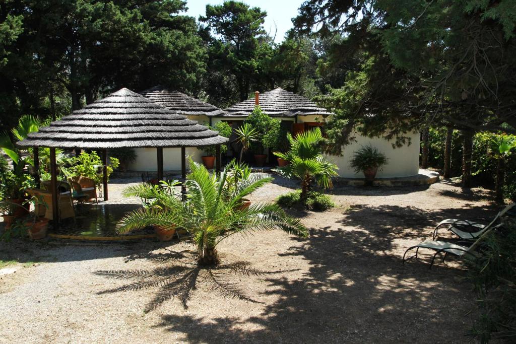 um grupo de casas de estilo hacienda com um banco e árvores em BOUTIQUE VILLA con accesso privato alla spiaggia em Caronia