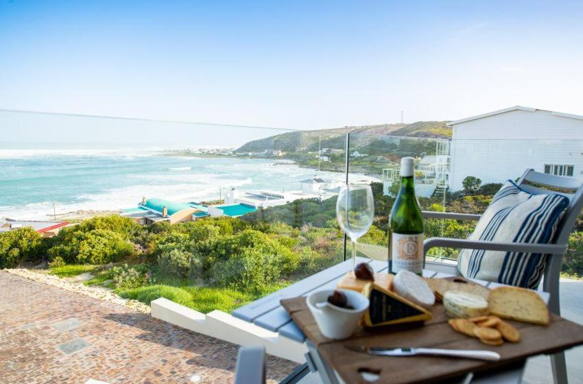 a table with a glass of wine and a plate of bread and cheese at Struisbaai Apartments in Struisbaai