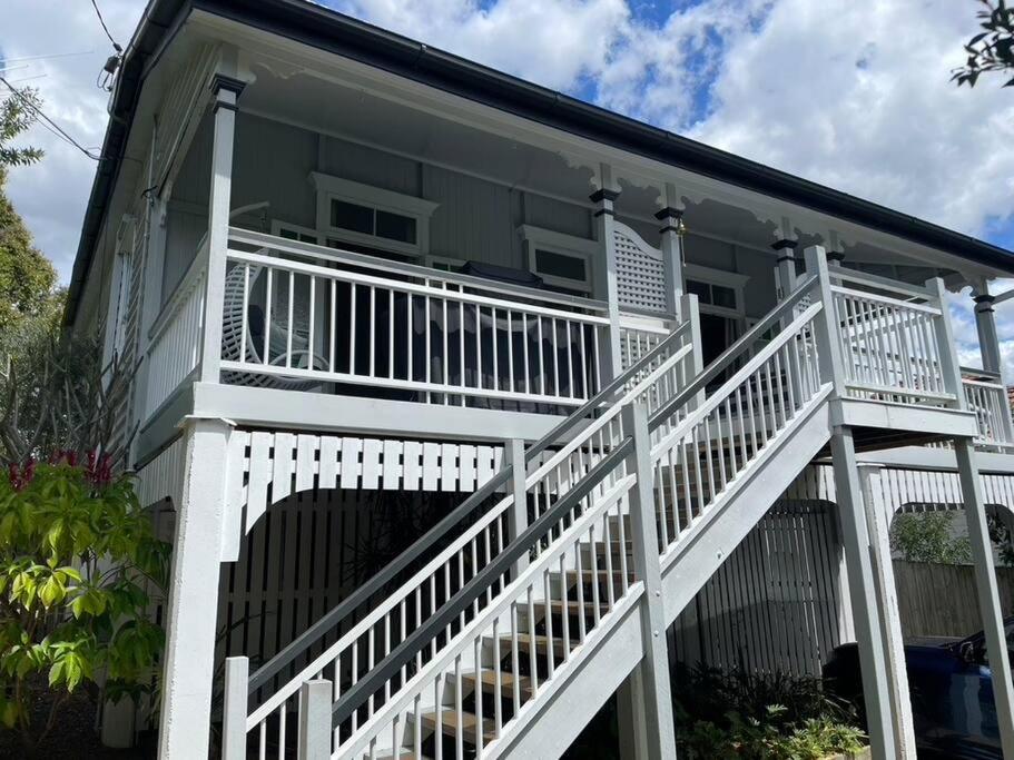 a large white house with a white staircase at Neat, Tidy and Central in Brisbane