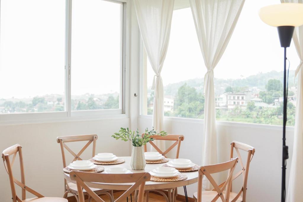een eetkamer met een tafel en stoelen en een raam bij Over Easy Apartment in Bandung