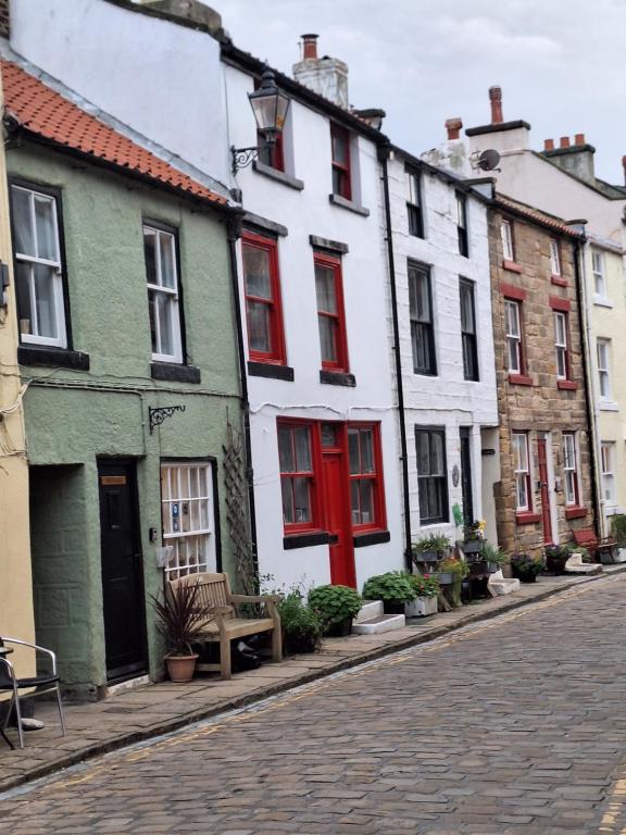 a row of houses with red doors on a street at The Cottage, High Street Staithes in Staithes