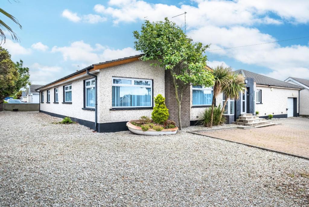 a house with a gravel driveway in front of it at Port Tara Holiday Home in Portballintrae