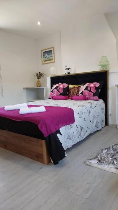 une chambre avec un grand lit avec des oreillers roses dans l'établissement Maison avec jardin Honfleur, à Honfleur