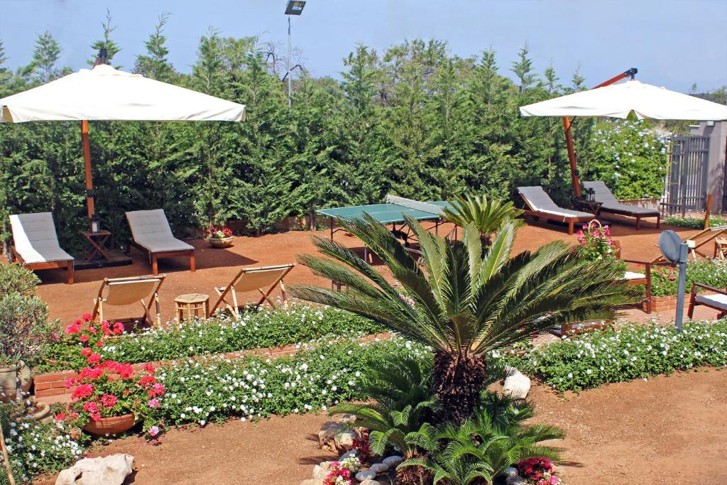 un giardino con sedie, ombrelloni e fiori di Villa Paradiso a Scopello