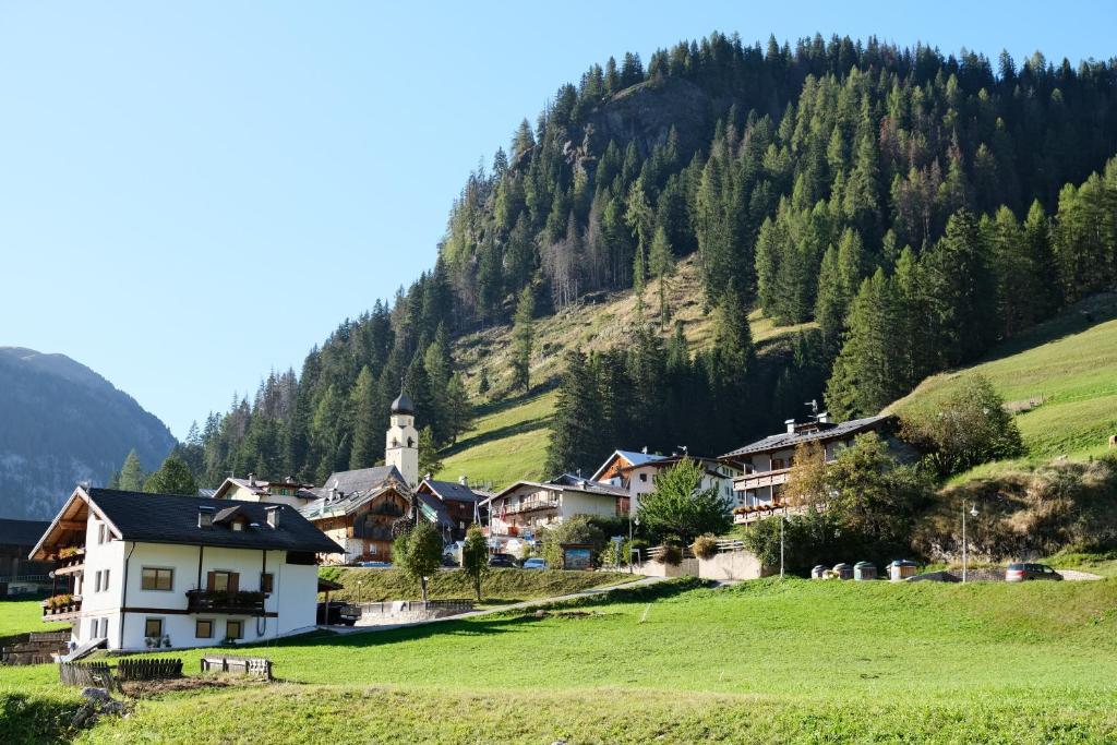 ein Dorf in den Bergen mit einer Kirche auf einem Hügel in der Unterkunft Gran Vernel Hause in Canazei