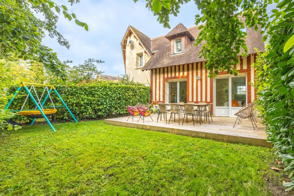 um quintal com um parque infantil e uma casa em Nice house with a yard and common pool - Deauville - Welkeys em Deauville
