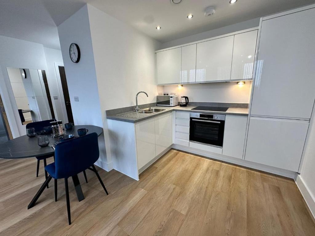 una cocina con armarios blancos, una mesa y una barra en 1 Bed Apartment near Old Trafford with free car park, en Mánchester