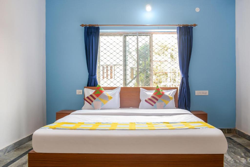 a bedroom with a large bed with blue walls and a window at OYO Home Elite Stay Near Shri Shri Shiridi Sai Mandir in Khandagiri