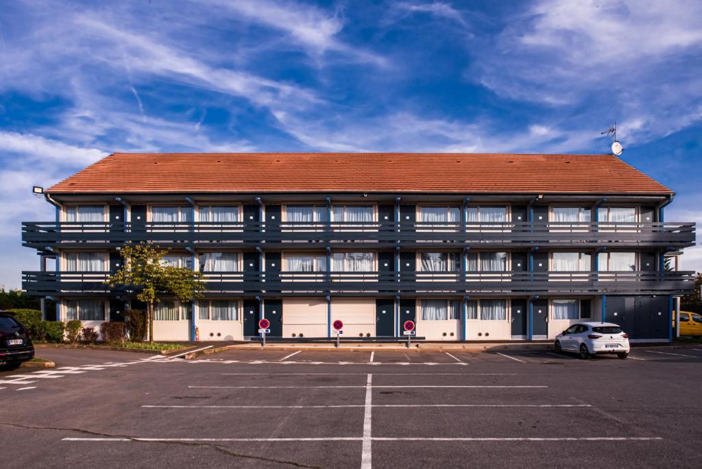 a large building with a parking lot in front of it at Kyriad Villeneuve Saint Georges - Hôtel rénové in Villeneuve-Saint-Georges