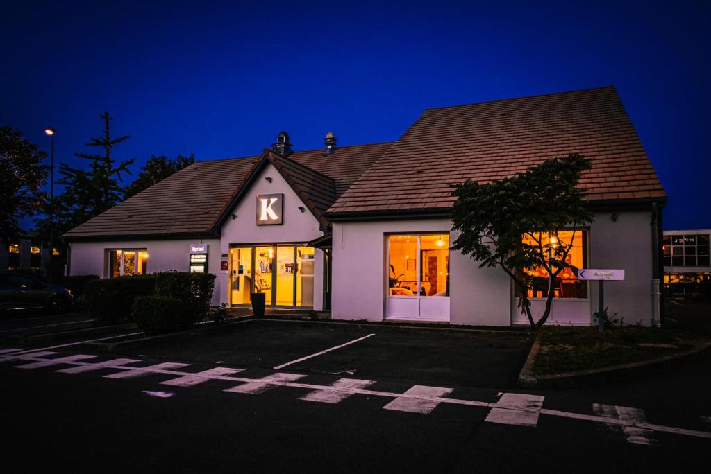 a white house with lights in the windows at night at Kyriad Villeneuve Saint Georges - Hôtel rénové in Villeneuve-Saint-Georges