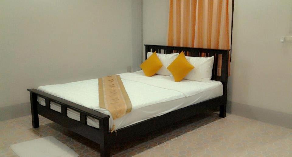 um quarto com uma cama com almofadas amarelas e brancas em MSD House em Ko Por