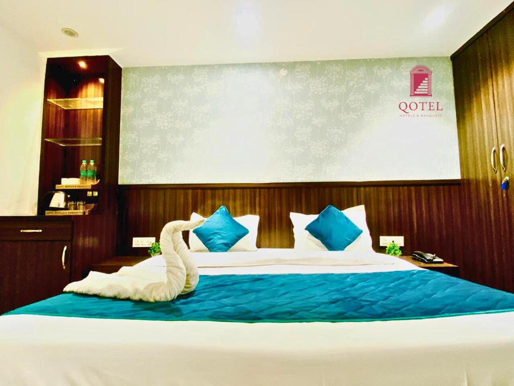 una camera da letto con un grande letto con cuscini blu e bianchi di Qotel B&B Hotel Rajouri Garden Above Ritu Marbel Near Rajouri Garden Metro Station a Nuova Delhi