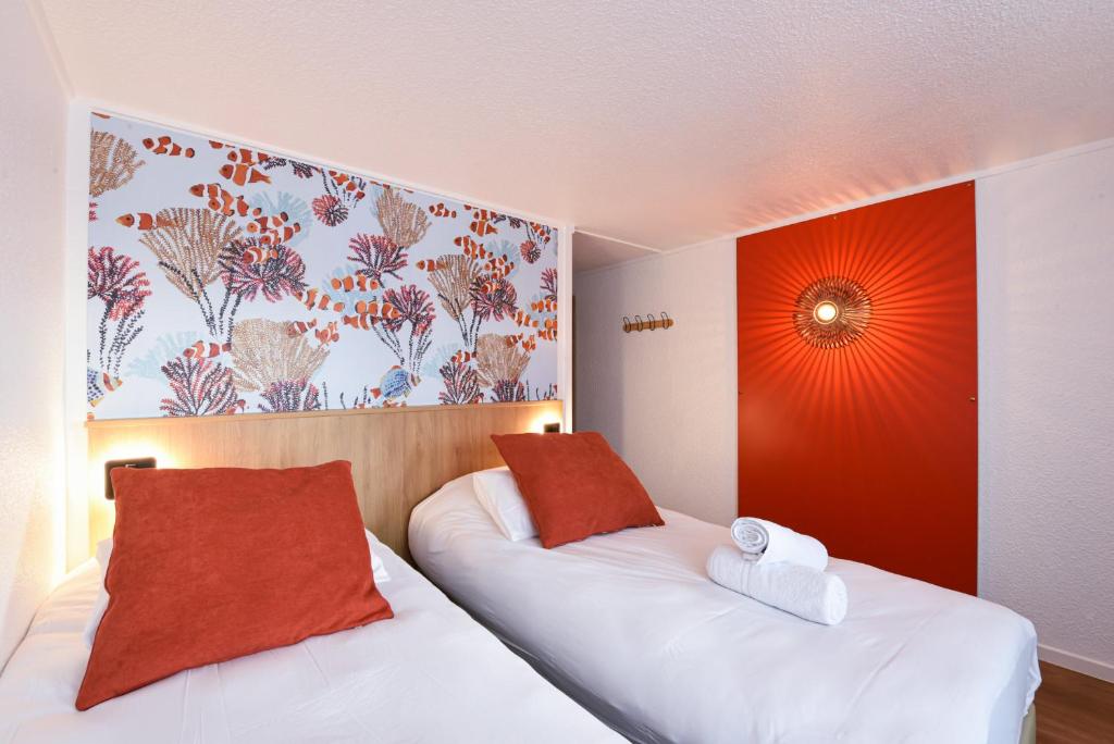 a hotel room with two beds with red and white pillows at Kyriad Villeneuve Saint Georges - Hôtel rénové in Villeneuve-Saint-Georges