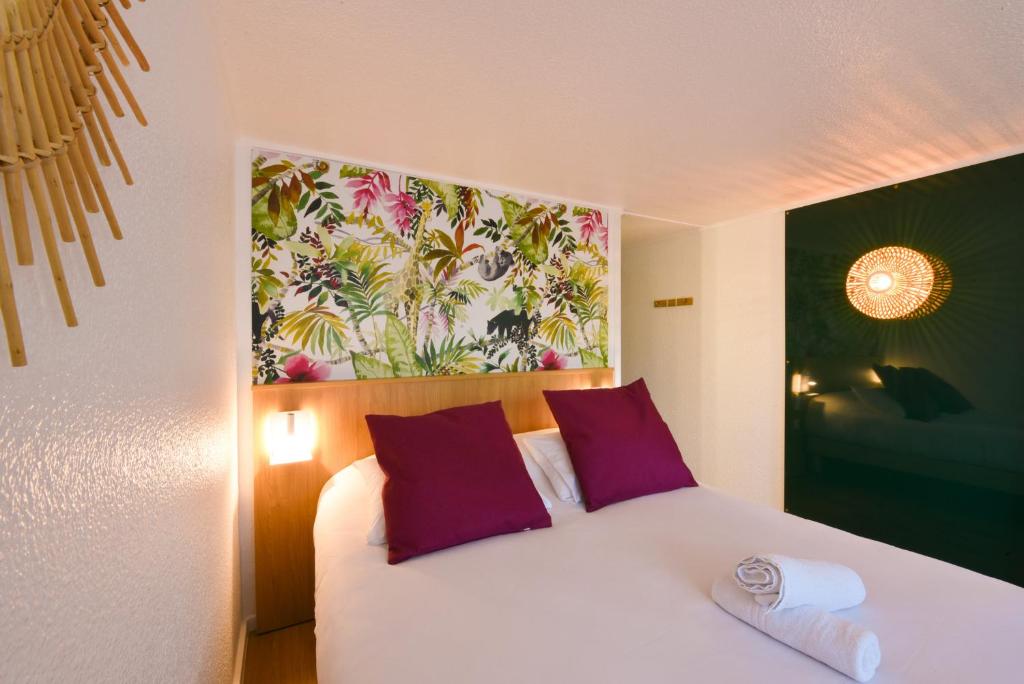 a bedroom with a bed with purple pillows and a painting at Kyriad Villeneuve Saint Georges - Hôtel rénové in Villeneuve-Saint-Georges