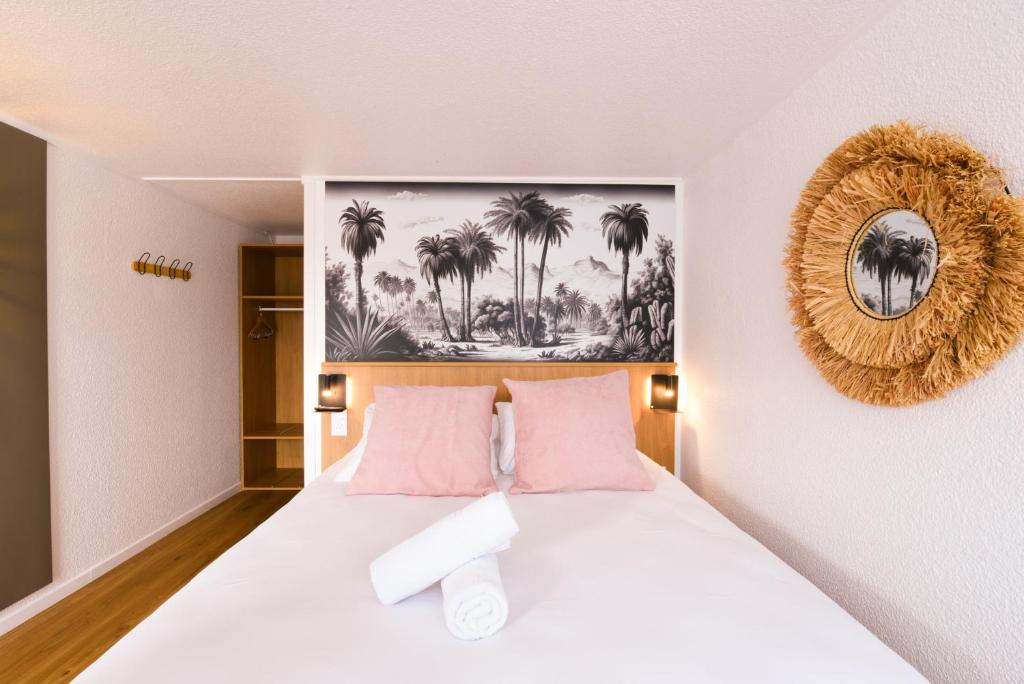 a bedroom with a white bed with pink pillows at Kyriad Villeneuve Saint Georges - Hôtel rénové in Villeneuve-Saint-Georges