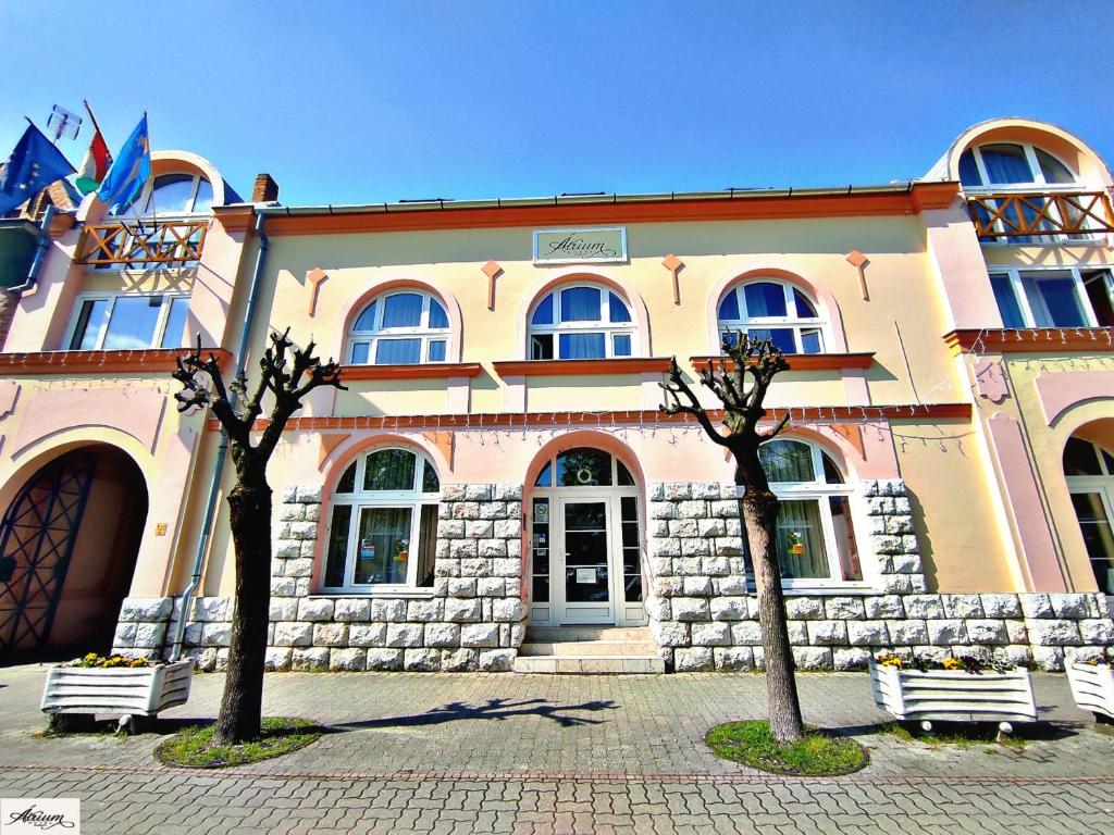 un bâtiment avec deux arbres devant lui dans l'établissement Átrium Hotel Harkány, à Harkány