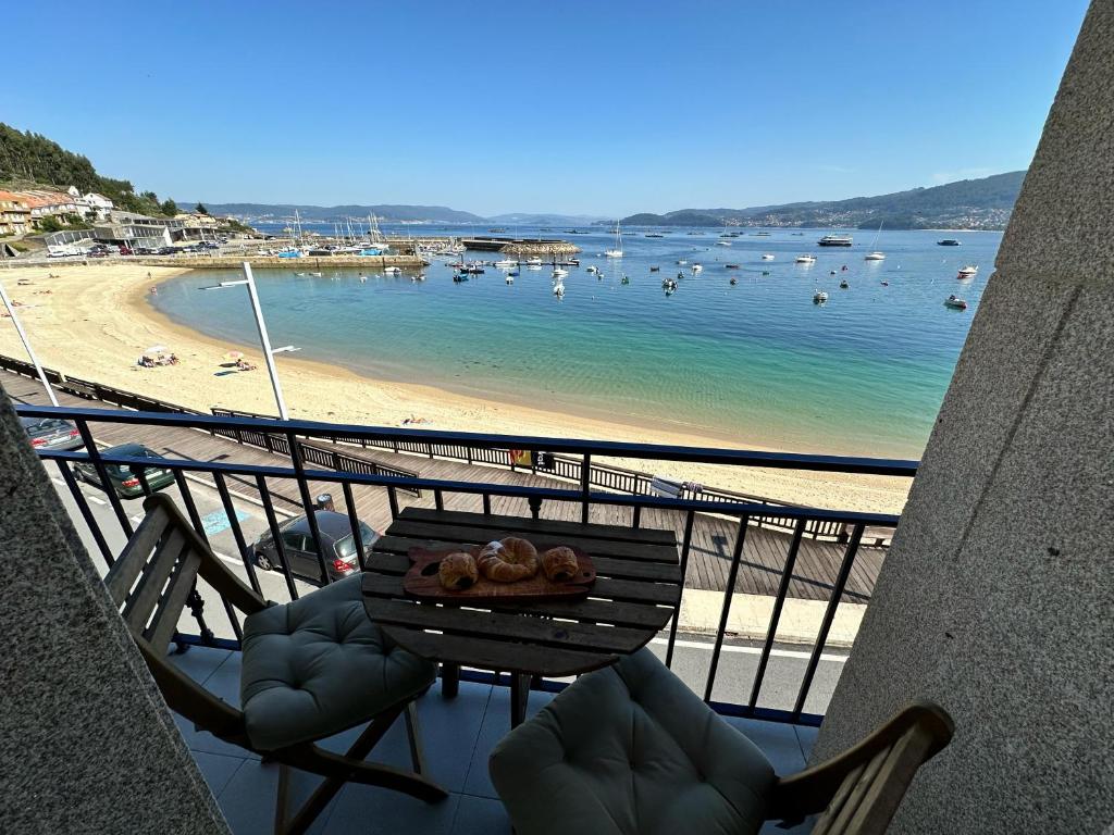 a balcony with a table and chairs and a beach at Mar de Beluso in Bueu