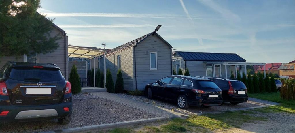 two cars parked in a parking lot next to a house at Domki Reval in Rewal