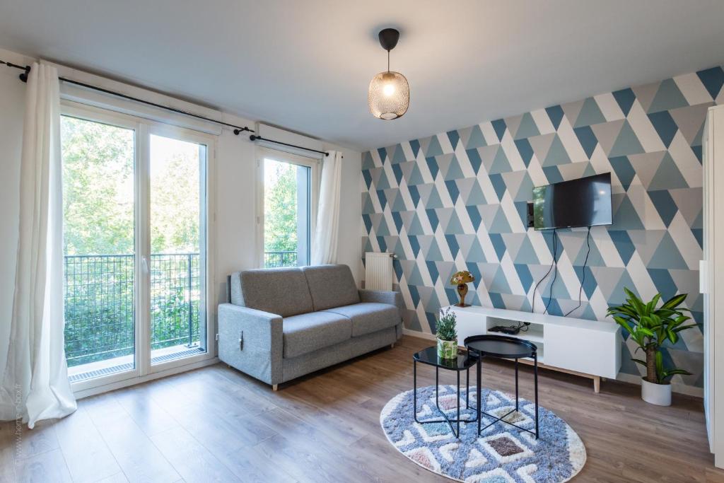 un salon avec un canapé et une télévision dans l'établissement Blue Pearl By Plaza, à Montévrain