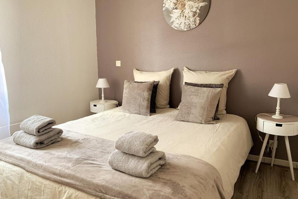 een slaapkamer met een groot bed en handdoeken bij Cosy Bohème Parking, RDC, Loggia, Wifi in Libourne