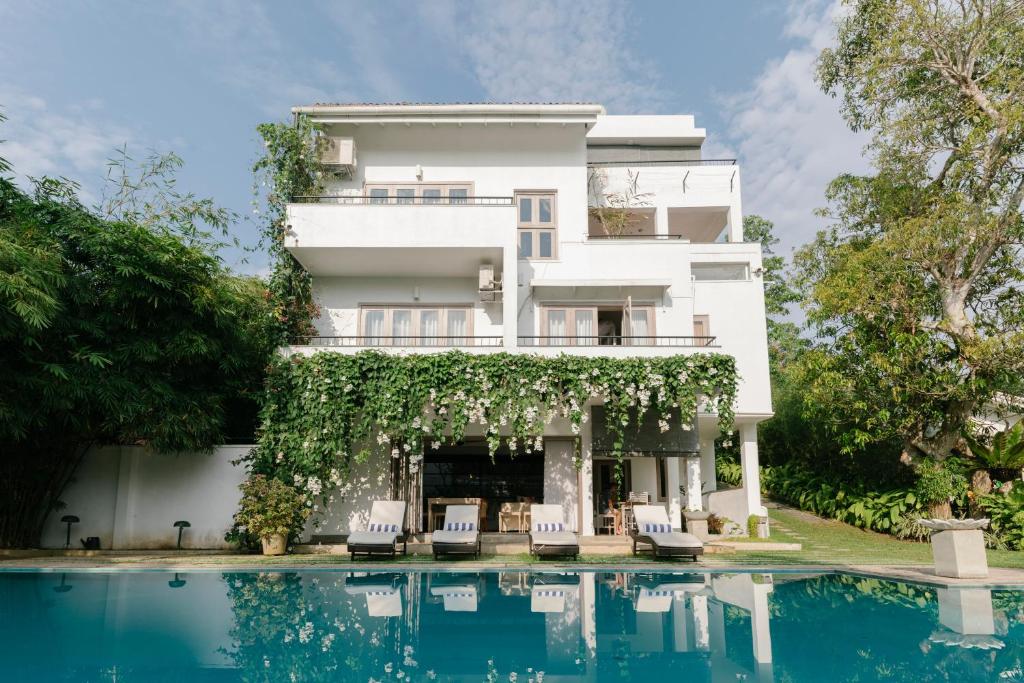 a house with a swimming pool in front of a building at Arahtis Lake Villa in Hikkaduwa