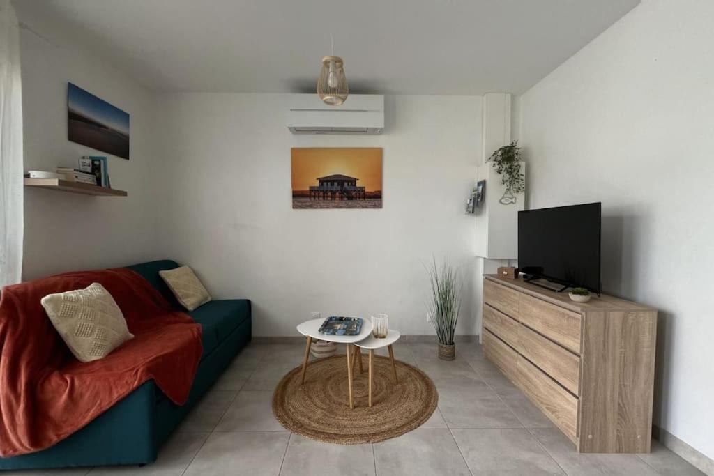 a living room with a couch and a tv at Studio tout confort + terrasse in Gujan-Mestras